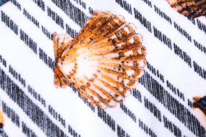 Toalla de playa con rayas multicolores y conchas marinas